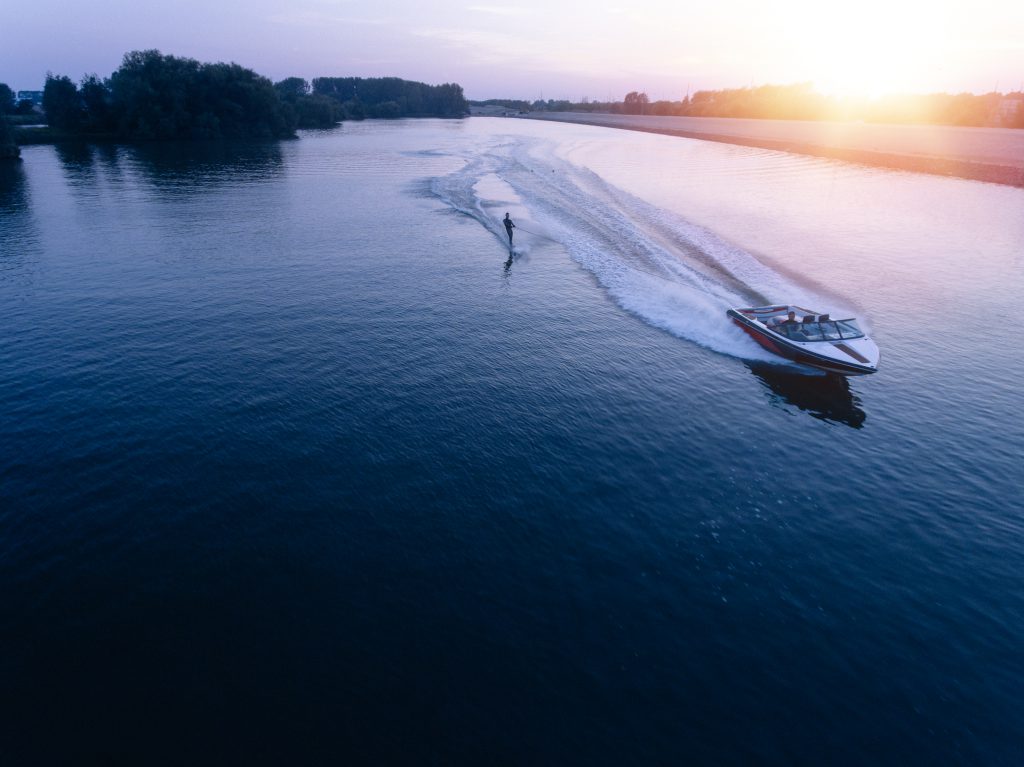 Skieur nautique à l'arrière d'un bateau à moteur sur un lac au coucher du soleil